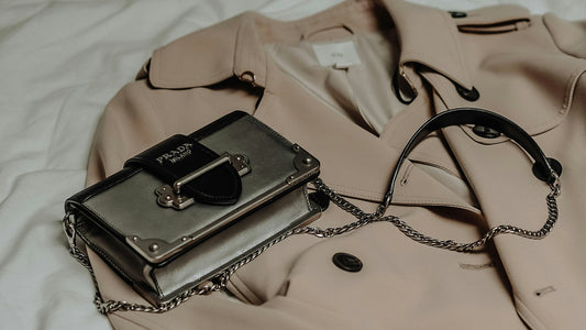 A structured leather bag resting on a camel trench coat