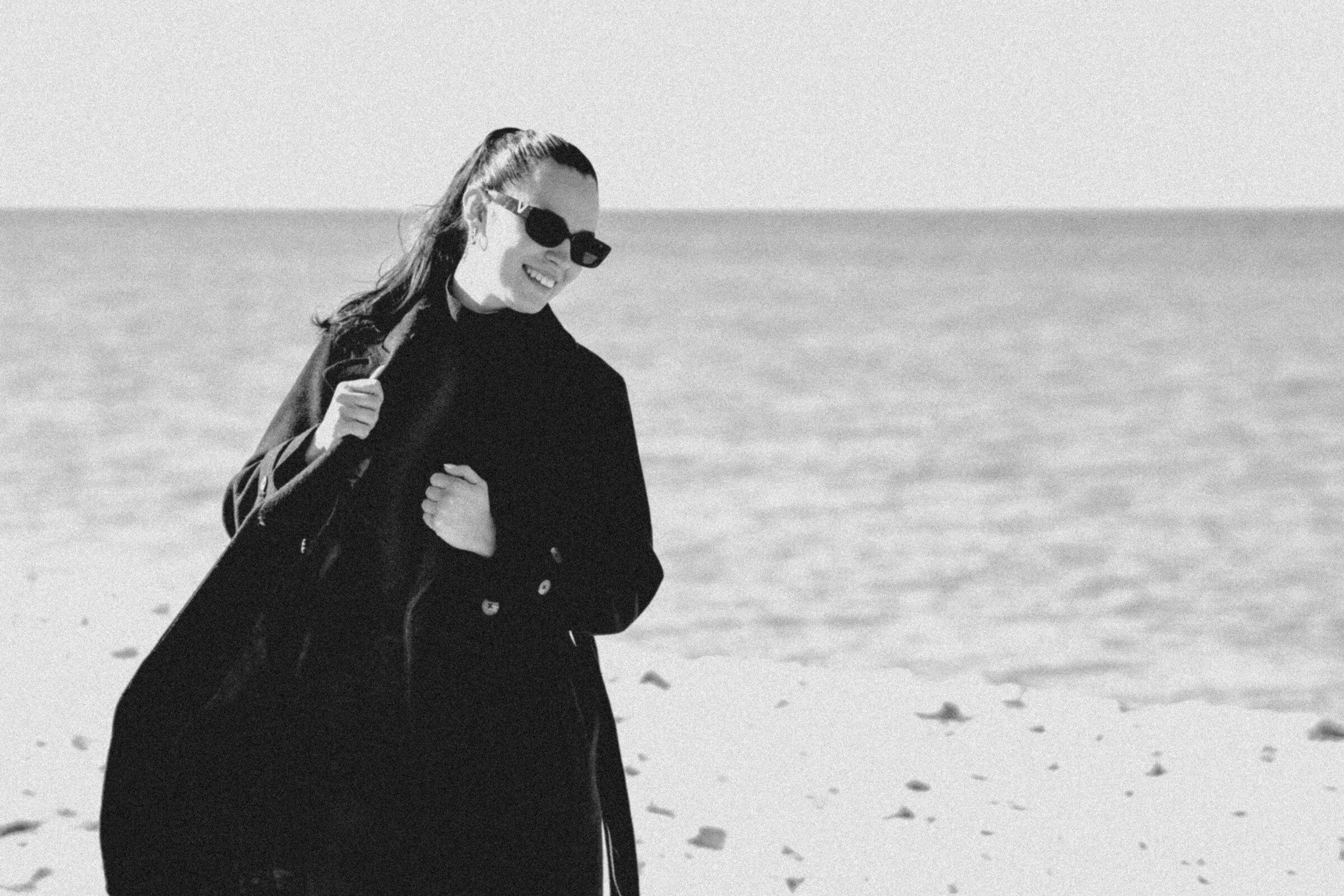 Model in a black coat by the sea